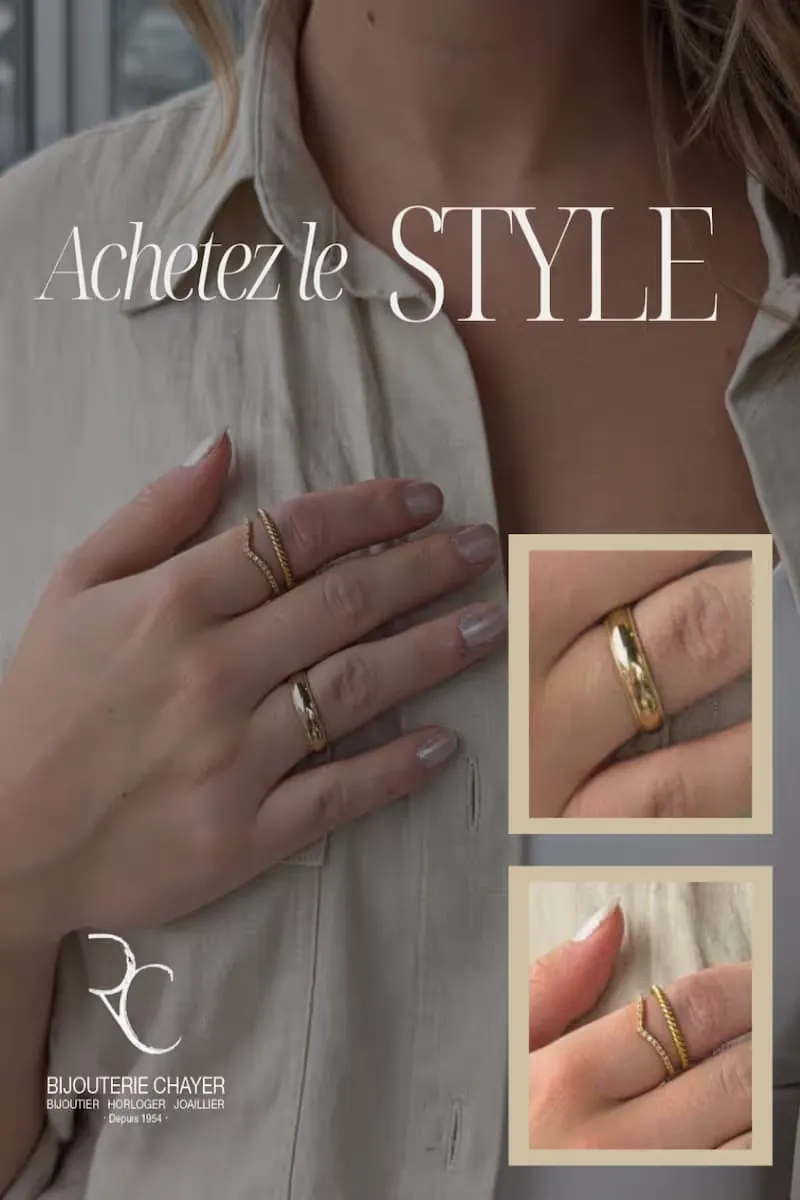 Main féminine portant une chemise beige avec plusieurs bagues dorées, dont une simple bague lisse et deux bagues fines décoratives.